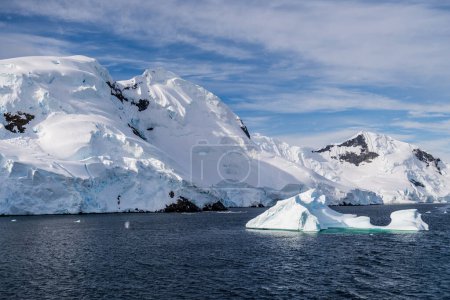A tranquil Antarctic landscape, near Graham passage along Charlotte Bay, highlighting stark reflections, rugged mountains, and impressive icebergs.