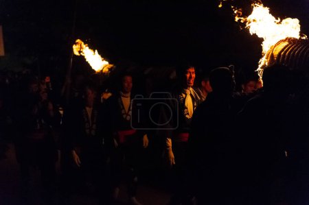 Photo for Miyajima, Japan - December 31, 2019. Participants of the Chinkasai Fire Festival at Itsukushima Shrine, near Hiroshima, carry large burning torches around the sea shore as part of a ritual to - Royalty Free Image
