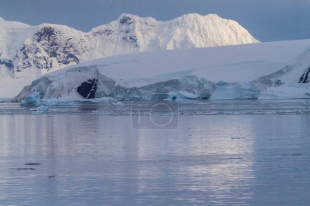 Photo for Icebergs and Glaciers align the coast of the Antarctic peninsula, and its many islands. A very tranquil sea reflects the early morning light in the Gerlache strait. - Royalty Free Image
