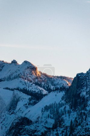 Foto de La luz del sol temprana que captura las cumbres nevadas de las montañas de Sierra nevada en el parque nacional de Yosemite, alrededor del amanecer en una mañana temprana del invierno. - Imagen libre de derechos