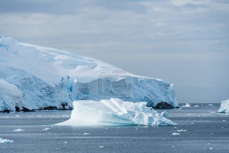 Foto de Un tranquilo paisaje antártico, cerca del paso de Graham a lo largo de la bahía de Charlotte, destacando reflejos crudos, montañas escarpadas e impresionantes icebergs. - Imagen libre de derechos