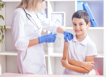 Photo for Vaccination of children, a little boy at a woman doctor's appointment, an injection in the arm - Royalty Free Image