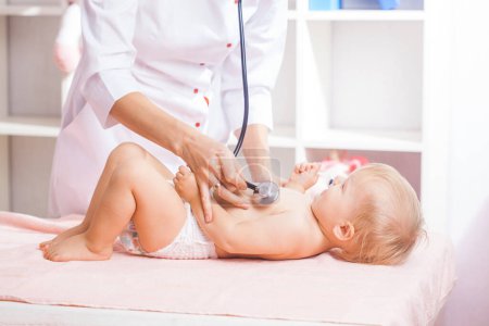 Téléchargez les photos : Femme Docteur examinant un petit bébé avec stéthoscope à la clinique. Concept de santé bébé - en image libre de droit
