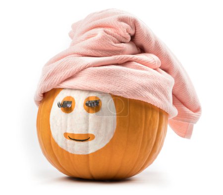 Foto de Pumpkin with facial mask and pinc towel isolated on the white. copy space - Imagen libre de derechos