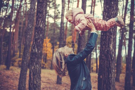 Téléchargez les photos : Drôles de jeux de famille dans la forêt d'automne, mère vomit l'enfant - en image libre de droit