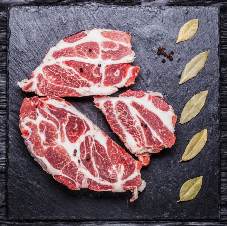Téléchargez les photos : Morceaux de viande crue sur une planche d'ardoise noire. concept culinaire - en image libre de droit