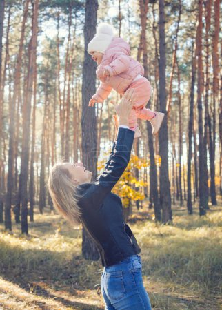Téléchargez les photos : Drôles de jeux de famille dans la forêt d'automne, mère vomit l'enfant - en image libre de droit