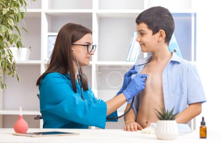 Photo for Woman doctor or pediatrician with stethoscope listening to heartbeat boys patient on medical exam at clinic. kid boy on medical examination checkup - Royalty Free Image