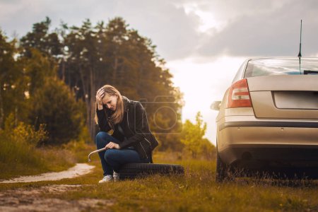 Photo for Woman on a car struck a wheel on the road. yourself repair on the side of the road - Royalty Free Image