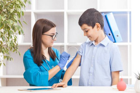 Photo for Vaccination of children, a little boy at a woman doctors appointment, an injection in the arm - Royalty Free Image