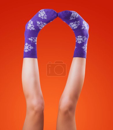 Téléchargez les photos : Female legs in christmas socks on orange background - en image libre de droit
