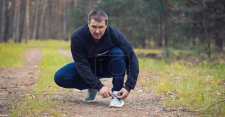 Photo for Runner tying shoelaces on sneakers. Morning jogging in the forest - Royalty Free Image