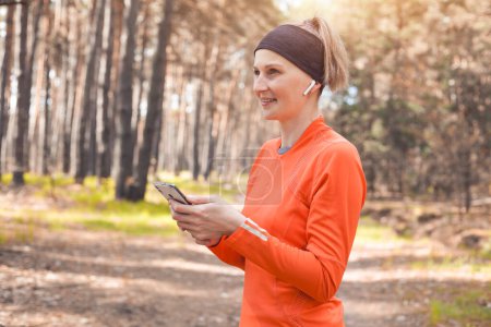 Téléchargez les photos : Jeune fille sur une course matinale dans une forêt de pins ensoleillée. entraînement cardio et mode de vie sain - en image libre de droit
