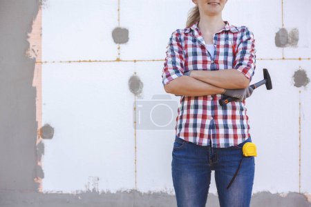 Aislamiento de la casa con espuma de polietileno. La trabajadora se para frente a una pared aislada con espuma plástica