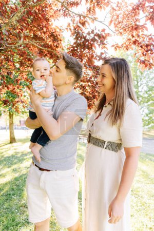 Porträt einer jungen Familie mit ihrem neun Monate alten Baby beim Spaß im öffentlichen Park
