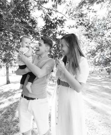 Retrato de una familia joven con su bebé de nueve meses divirtiéndose en el parque público