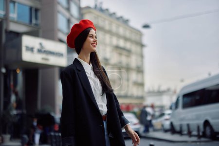 Foto de Una mujer sonriente con dientes de negocios camina en la ciudad contra el telón de fondo de los edificios de oficinas, ropa elegante y maquillaje, paseo de primavera, viajes. Foto de alta calidad - Imagen libre de derechos