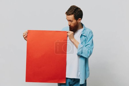 Foto de Retrato de un hombre adulto sobre un fondo gris con un trozo de papel rojo para su diseño y texto, diseño, espacio de copia, espacio para texto. Foto de alta calidad - Imagen libre de derechos