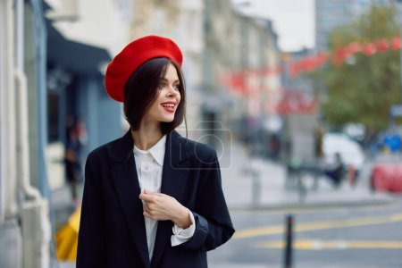 Téléchargez les photos : Mode femme sourire printemps marche dans la ville dans des vêtements élégants avec des lèvres rouges et béret rouge, Voyage, couleur cinématographique, style vintage rétro, mode de vie urbaine. Photo de haute qualité - en image libre de droit