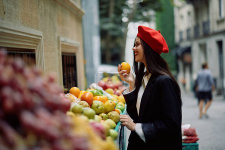 Téléchargez les photos : Femme sourire avec des dents promenades touristiques dans le marché de la ville avec des fruits et légumes choisir des marchandises, vêtements et maquillage à la mode élégant, marche de printemps, Voyage. Photo de haute qualité - en image libre de droit