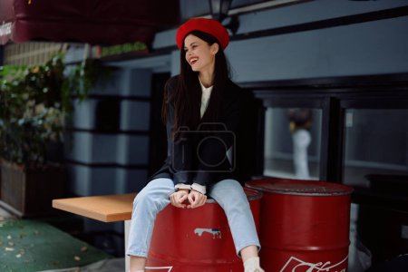 Téléchargez les photos : Femme assise devant un café et un bar dans une rue de la ville, image de mode élégante de vêtements, vacances et voyages, promenade en ville. Photo de haute qualité - en image libre de droit