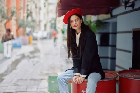 Téléchargez les photos : Femme joyeuse sourire avec des dents assis à l'extérieur d'un café et un bar dans une rue de la ville, look de mode élégant de vêtements, vacances et Voyage. Photo de haute qualité - en image libre de droit