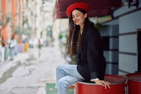Téléchargez les photos : Belle femme sourire avec des dents assis à l'extérieur d'un café et un bar dans une rue de la ville, look élégant robe de fantaisie, vacances et Voyage. Photo de haute qualité - en image libre de droit