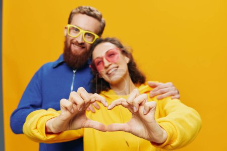 Photo for Man and woman couple smiling cheerfully and crooked with glasses, on yellow background, symbols signs and hand gestures, family shoot, newlyweds. High quality photo - Royalty Free Image