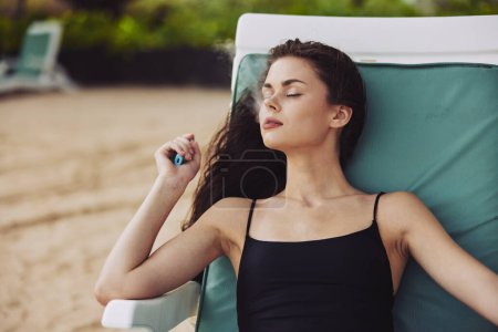 Foto de Mujer vacaciones relajación azul estilo de vida playa vacaciones sonriente sombrero tropical silla de estar relajarse arena océano chica resort mar playa tumbado solarium joven - Imagen libre de derechos