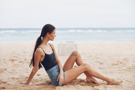 Téléchargez les photos : Femme été insouciant assis nature mer Voyage plage détendre sable bronzage sourire liberté vacances attrayant côte eau joli sexy style de vie caucasien - en image libre de droit