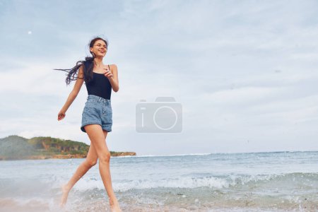 Foto de Salida del sol mujer mar sonrisa corriendo viaje caminar relajarse chica puesta del sol bikini pelo playa joven sonriente verano mujer ola sexy estilo de vida despreocupado - Imagen libre de derechos