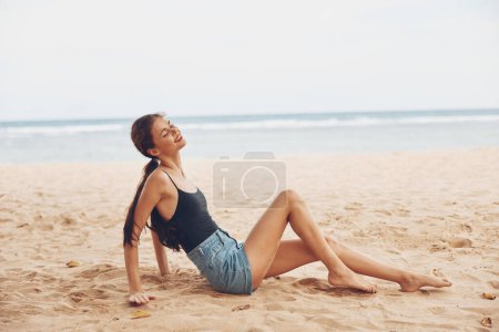 Téléchargez les photos : Liberté femme assis nature cheveux sable modèle naturel mer été bronzage seul sourire vue jolie blanc arrière plage long bali océan vacances Voyage - en image libre de droit
