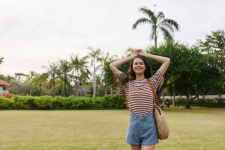 Foto de Sonriente mujer moda hipster caminar libertad divertido bolsa parque naturaleza estilo de vida sombrero bali camiseta sonrisa activo sol pradera hermoso tranquilo verano - Imagen libre de derechos
