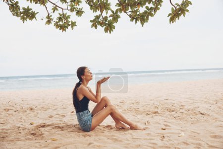 Foto de Despreocupado mujer vacaciones moda sentado arena sonrisa bastante largo playa modelo joven adulto mar libertad belleza cuerpo naturaleza caucásico pelo viaje vacaciones - Imagen libre de derechos