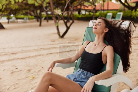 Téléchargez les photos : Femme chaise longue fille profiter de repos couché eau jeune plage attrayante loisirs bleu océan bronzage sable mer exotique souriant style de vie resort relax - en image libre de droit