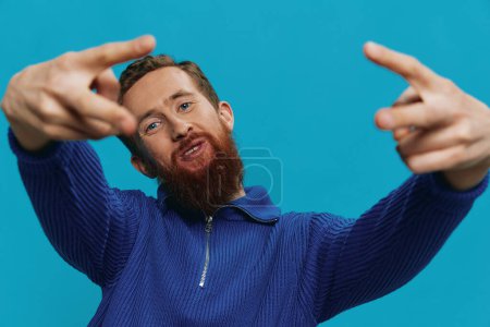 Photo for Portrait of a man in a sweater smile and happiness, hand signs and symbols, on a blue background. Lifestyle positive, copy place. High quality photo - Royalty Free Image