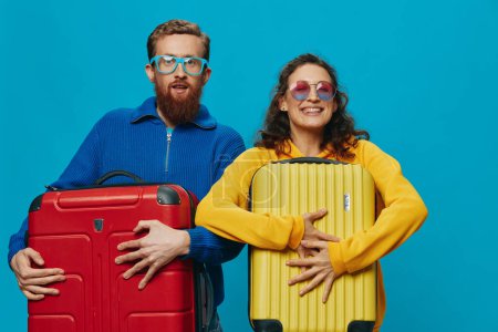 Foto de Mujer y hombre sonríen maletas en la mano con amarillo y rojo maleta sonrisa diversión, sobre fondo azul, embalaje para un viaje, viaje de vacaciones familiares. Foto de alta calidad - Imagen libre de derechos