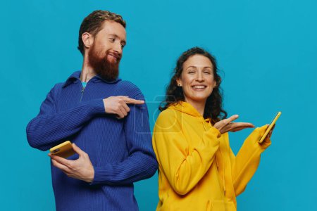 Photo for Woman and man cheerful couple with phones in their hands crooked smile cheerful, on blue background. The concept of real family relationships, talking on the phone, work online. High quality photo - Royalty Free Image