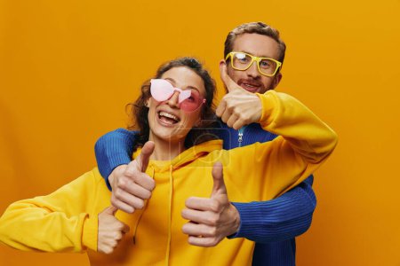 Photo for Man and woman couple smiling cheerfully and crooked with glasses, on yellow background, symbols signs and hand gestures, family shoot, newlyweds. High quality photo - Royalty Free Image