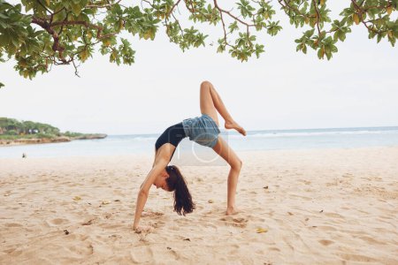 Photo for Woman gymnastics outdoor exercise female bikini lifestyle sport young bridge pose stretching calm practice training beach yoga sky healthy fitness bend - Royalty Free Image
