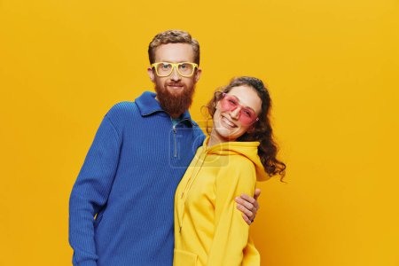 Téléchargez les photos : Couple homme et femme souriant joyeusement et tordu avec des lunettes, sur fond jaune, symboles signes et gestes de la main, tournage en famille, jeunes mariés. Photo de haute qualité - en image libre de droit