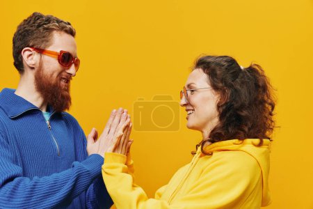 Foto de Pareja de hombres y mujeres sonriendo alegremente y torcidos con gafas, sobre fondo amarillo, símbolos signos y gestos de la mano, sesión familiar, recién casados. Foto de alta calidad - Imagen libre de derechos