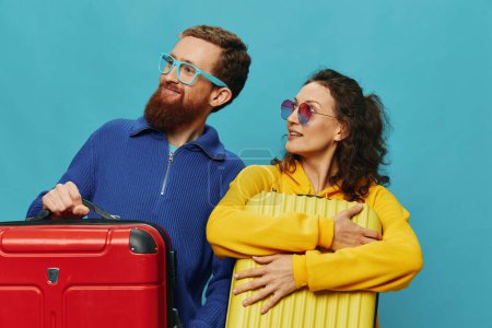 Téléchargez les photos : Femme et homme sourient valises à la main avec jaune et rouge valise sourire amusant, sur fond bleu, emballage pour un voyage, voyage de vacances en famille. Photo de haute qualité - en image libre de droit