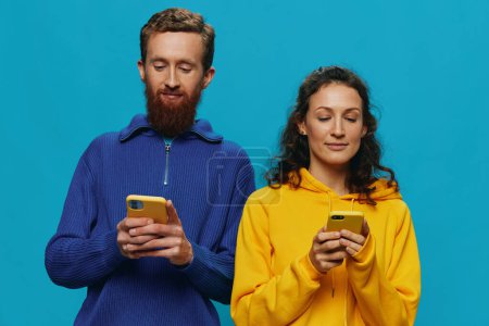 Photo for Woman and man cheerful couple with phones in their hands crooked smile cheerful, on blue background. The concept of real family relationships, talking on the phone, work online. High quality photo - Royalty Free Image