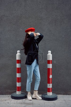Foto de Mujer de moda de pie en la calle frente a la ciudad y la carretera trabaja turista en ropa elegante con labios rojos y boina roja, viajes, color cinematográfico, estilo vintage retro. Foto de alta calidad - Imagen libre de derechos