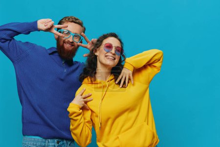 Photo for A woman and a man fun couple cranking and showing signs with their hands smiling cheerfully, on a blue background, The concept of a real relationship in a family. High quality photo - Royalty Free Image