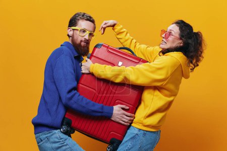 Foto de Mujer y hombre sonriendo, maletas en la mano con maleta amarilla y roja sonriendo alegre y torcida, fondo amarillo, yendo en un viaje, viaje de vacaciones en familia, recién casados. Foto de alta calidad - Imagen libre de derechos