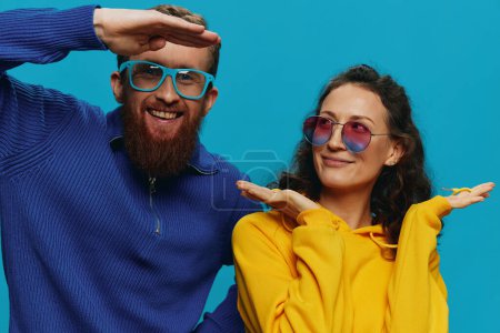 Photo for A woman and a man fun couple cranking and showing signs with their hands smiling cheerfully, on a blue background, The concept of a real relationship in a family. High quality photo - Royalty Free Image