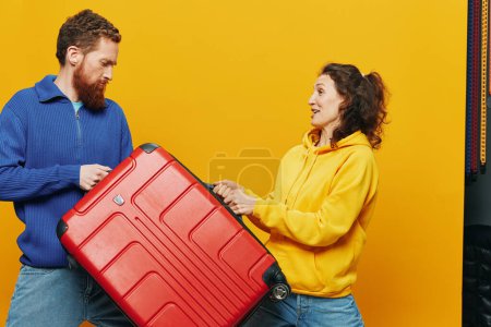 Photo for Woman and man smiling, suitcases in hand with yellow and red suitcase smiling merrily and crooked, yellow background, going on a trip, family vacation trip, newlyweds. High quality photo - Royalty Free Image