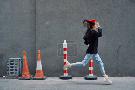 Photo for Fashion woman running down the street in front of the city tourist in stylish clothes with red lips and red beret, travel, cinematic color, retro vintage style, late to work. High quality photo - Royalty Free Image